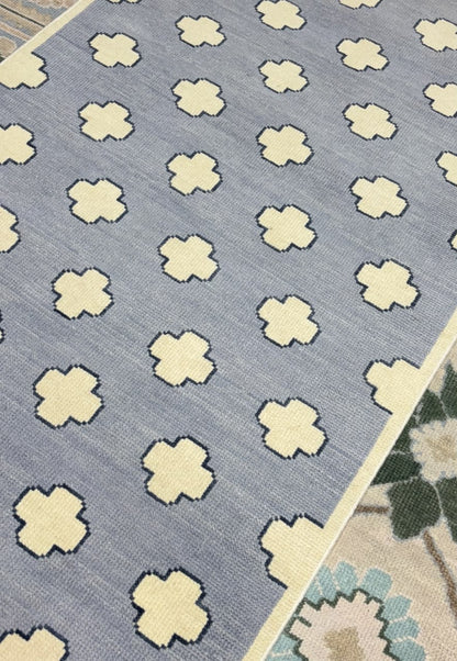 Angled view of a minimalist Scandinavian wool rug in dusty blue and ivory.