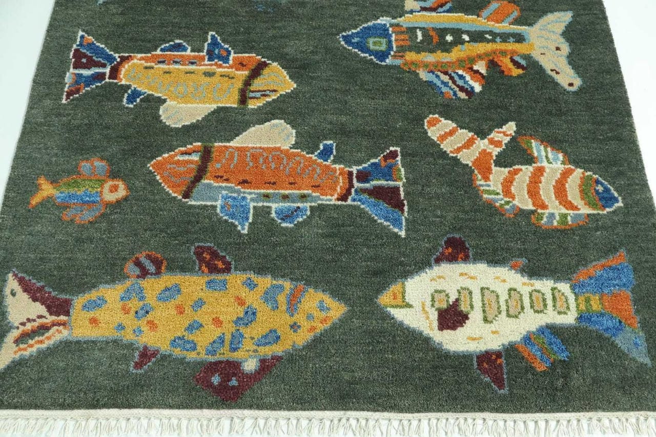 Close-up of handmade green fish area rug with colorful coastal fish motifs and soft wool texture