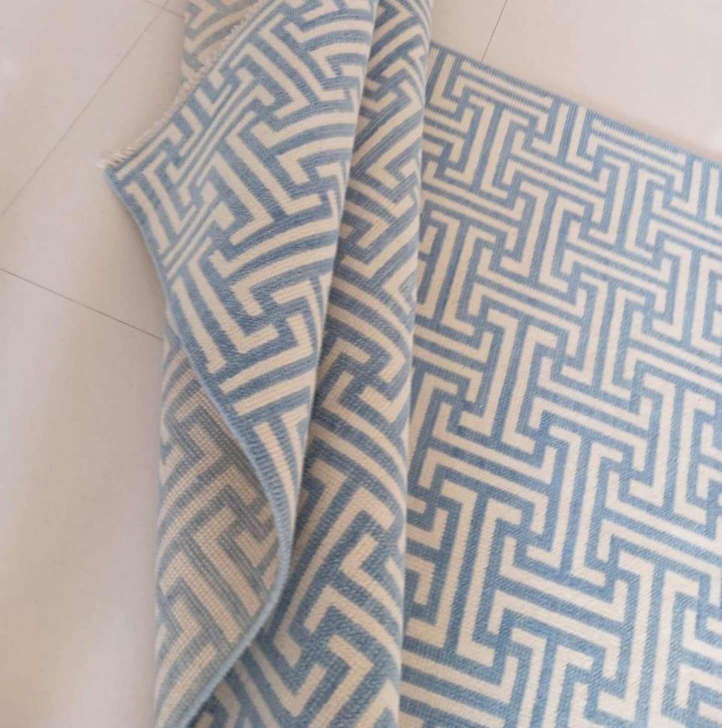 Folded view of handwoven flatweave wool rug in blue and ivory