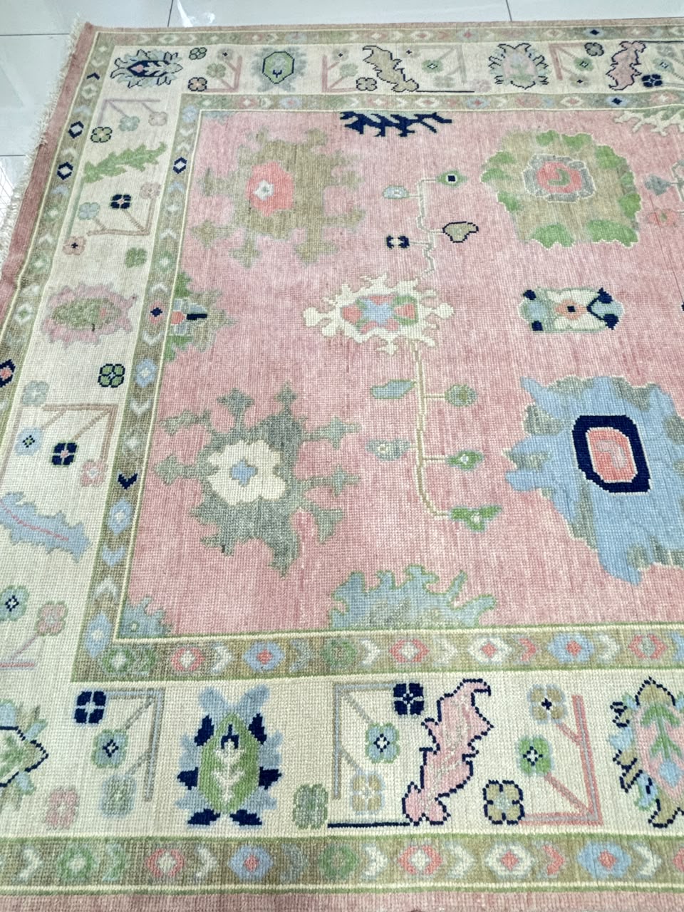 Full view of handmade blush pink Oushak area rug with traditional floral pattern