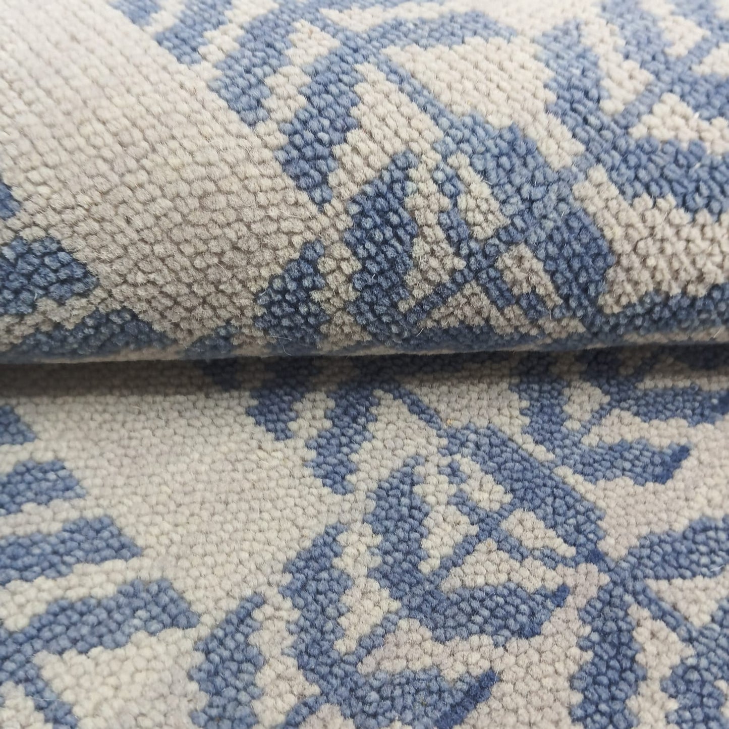 Close texture detail of geometric blue and ivory handwoven wool area rug