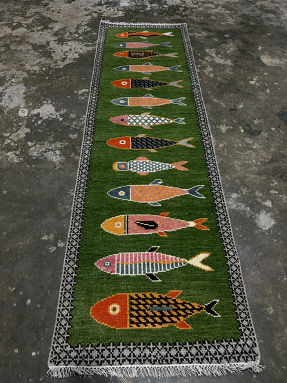 Hand-knotted green wool runner rug with colourful fish motifs and geometric border