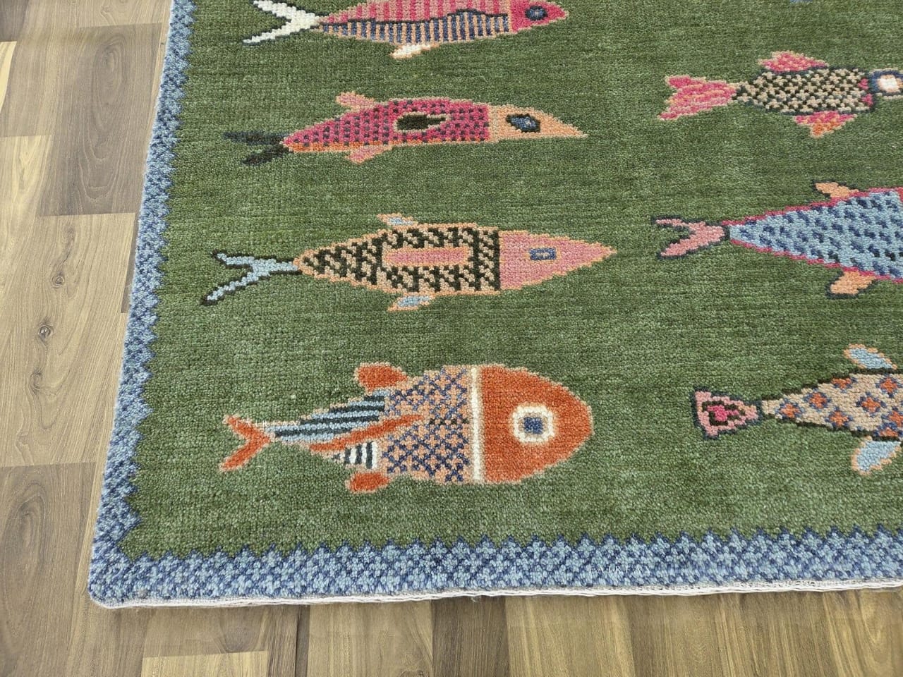 Corner detail of olive green fish area rug with colorful nautical fish patterns