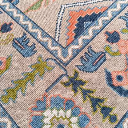 Detailed border of a handmade beige and dusty blue vintage Oushak rug with traditional floral motifs and wool texture.
