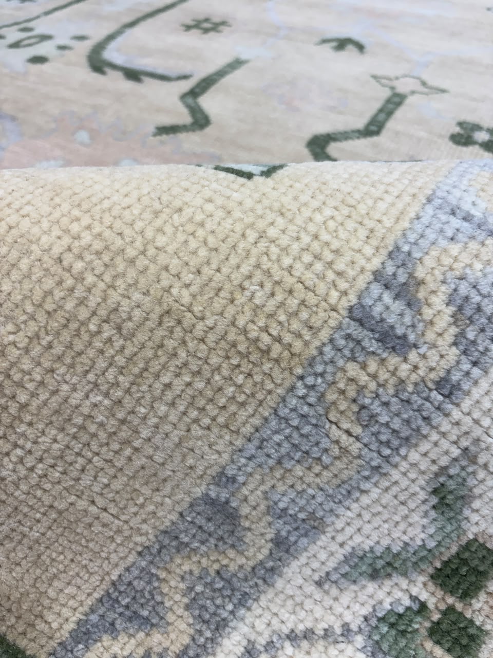 Handmade beige wool rug showing detailed woven texture and blue pattern