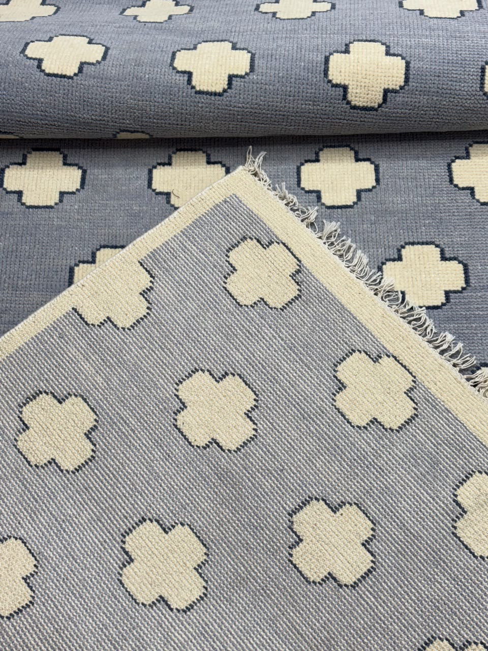 Folded corner of a handmade dusty blue wool rug highlighting clean edge finishing and craftsmanship.