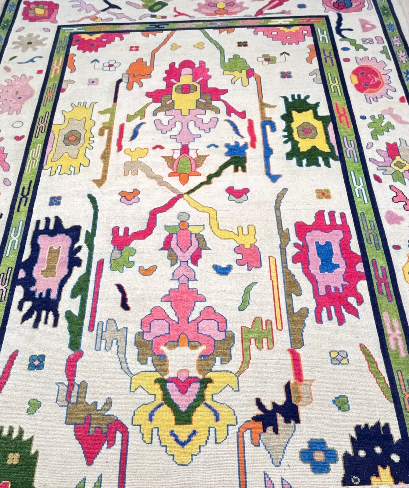 Handmade Scandinavian folk art wool rug featuring colorful geometric motifs on an ivory background with a green decorative border.