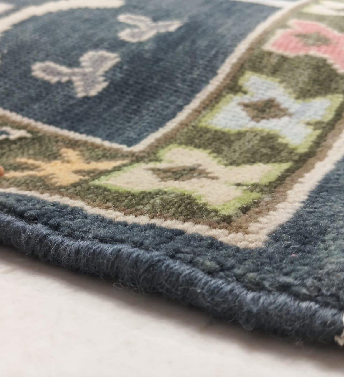 Hand-finished edge detail of navy blue wool rug