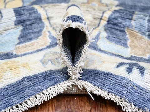 Folded handmade blue wool rug showing medium pile thickness and premium craftsmanship.