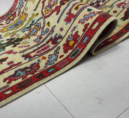 Folded cream and red Oushak runner rug displaying thickness and texture