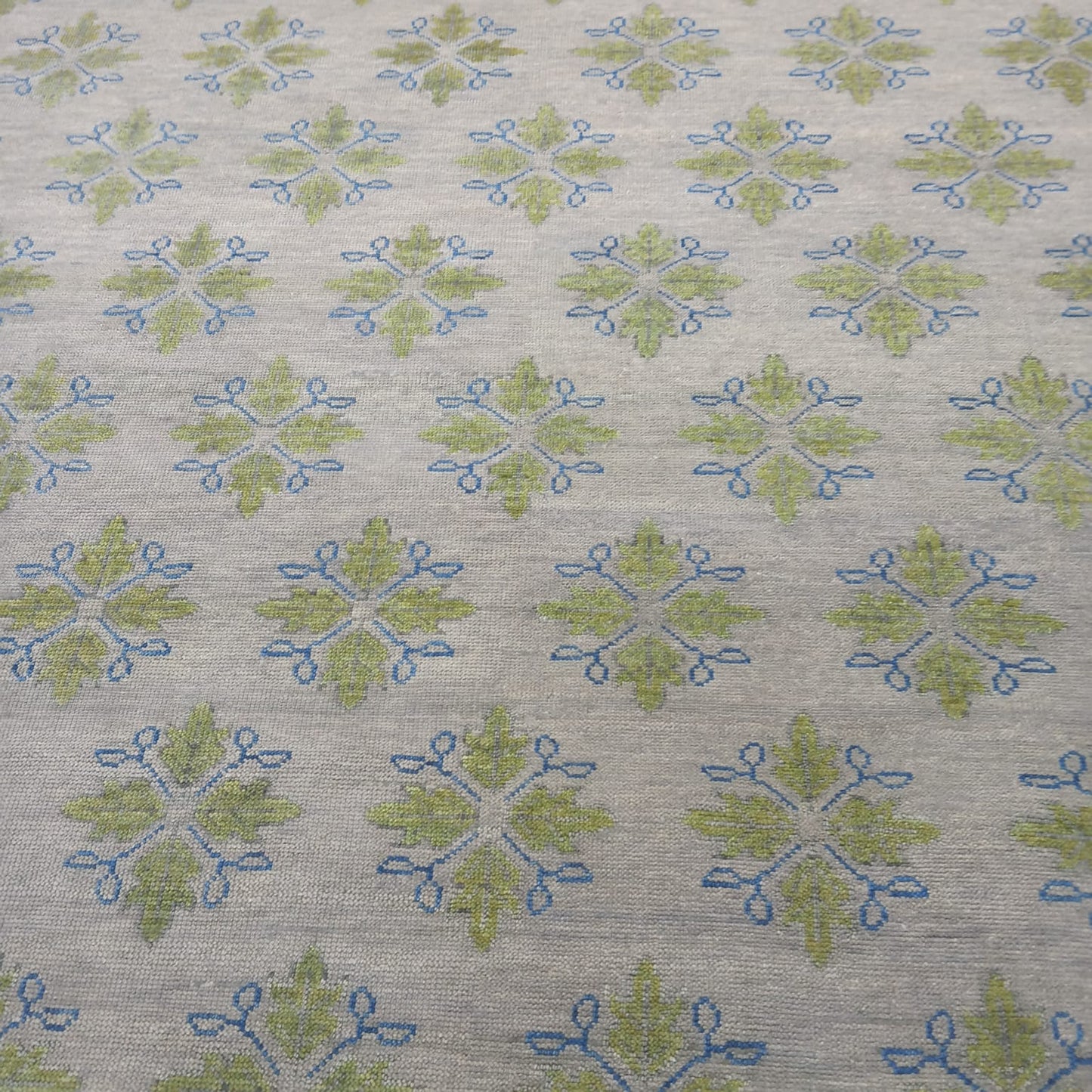Handmade ivory wool area rug with sage green botanical motifs and blue accents for modern living room décor
