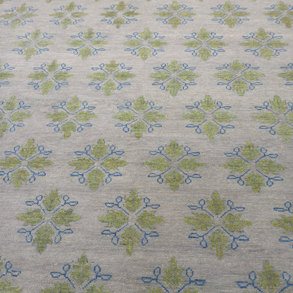 Handmade ivory wool area rug with sage green botanical motifs and blue accents for modern living room décor