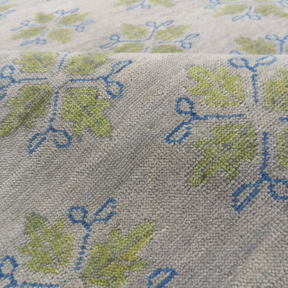 Close-up texture of handmade wool botanical rug in ivory, sage green and blue