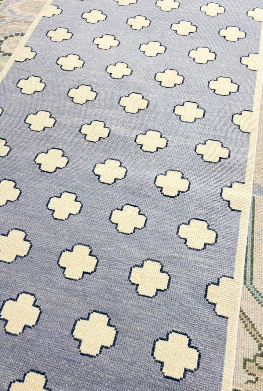 Handwoven dusty blue rug with repeating geometric pattern for contemporary interiors.