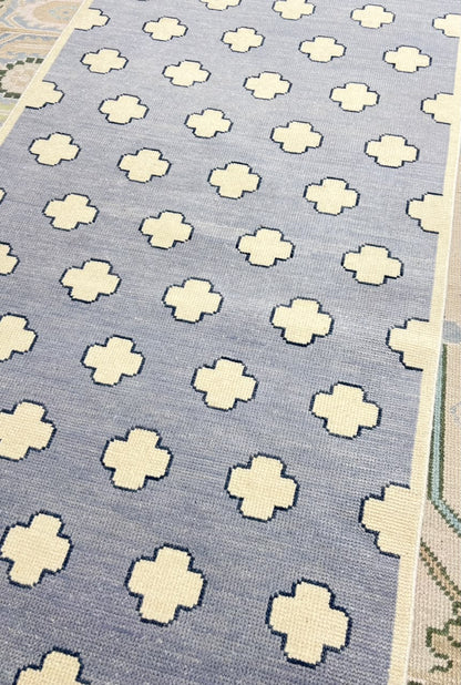 Handwoven dusty blue rug with repeating geometric pattern for contemporary interiors.