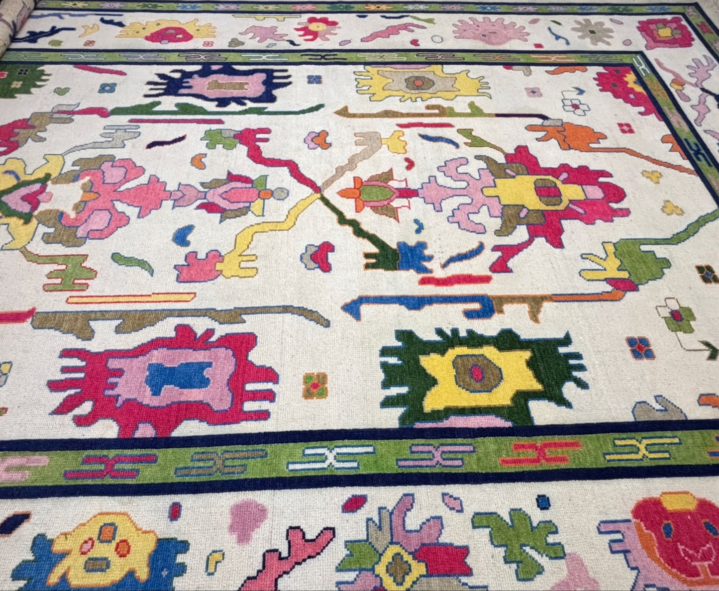 Close-up of the decorative green border and colorful geometric motifs on a handmade Scandinavian wool rug.