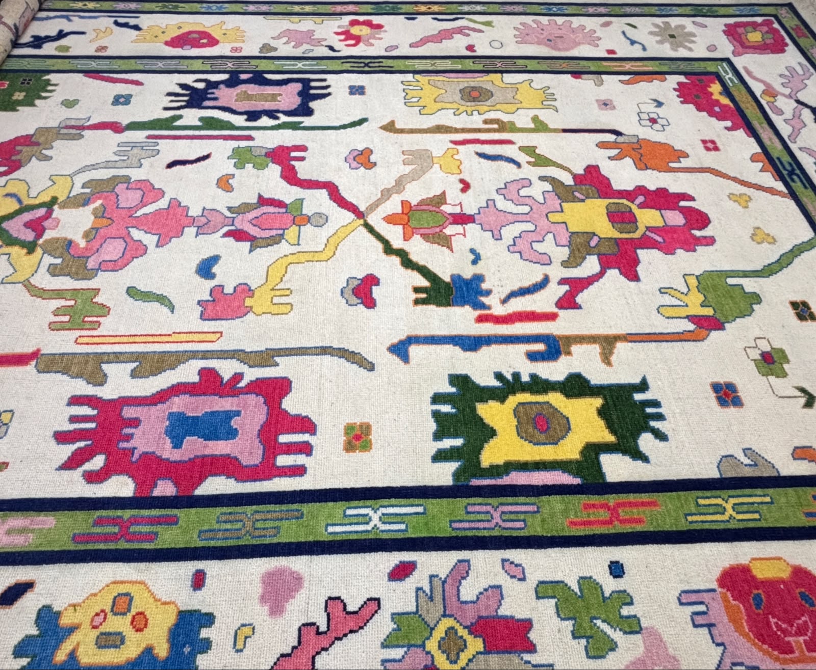 Close-up of the decorative green border and colorful geometric motifs on a handmade Scandinavian wool rug.