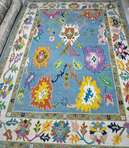 Handmade sky blue contemporary Oushak wool rug with colorful botanical motifs and ivory floral border