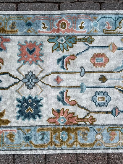 Handmade vintage Oushak runner rug close-up featuring ivory wool with pastel floral motifs and a sky blue border.