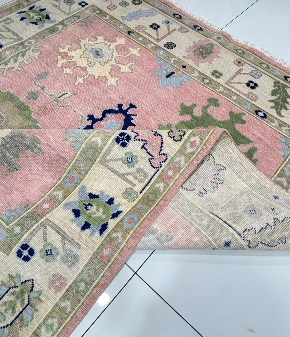 Folded corner of handmade blush pink Oushak rug showing durable wool construction