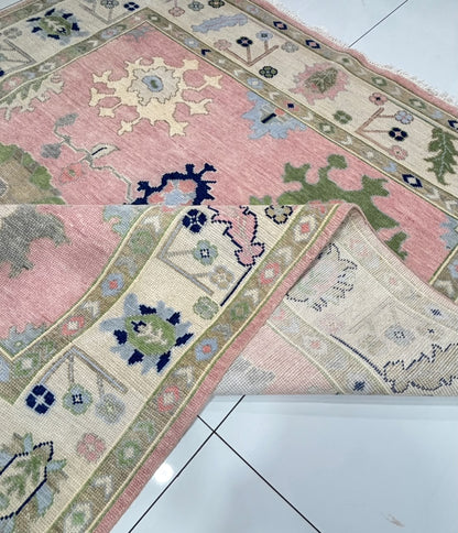 Folded corner of handmade blush pink Oushak rug showing durable wool construction