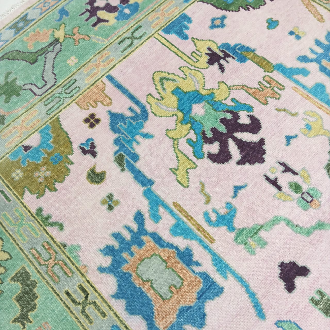 Close-up of a pastel pink and mint green patterned rug with geometric designs.