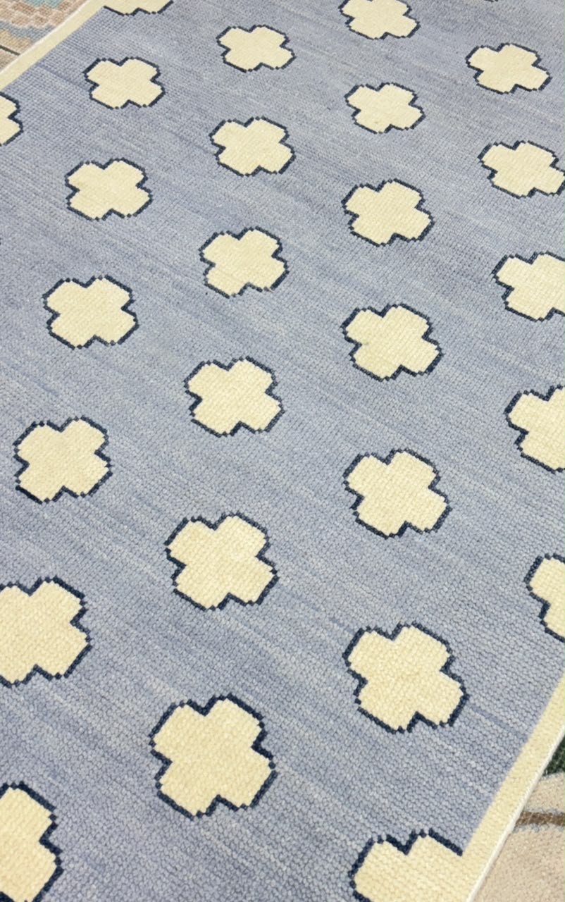 Textured close-up of a blue trellis wool rug handcrafted in India.