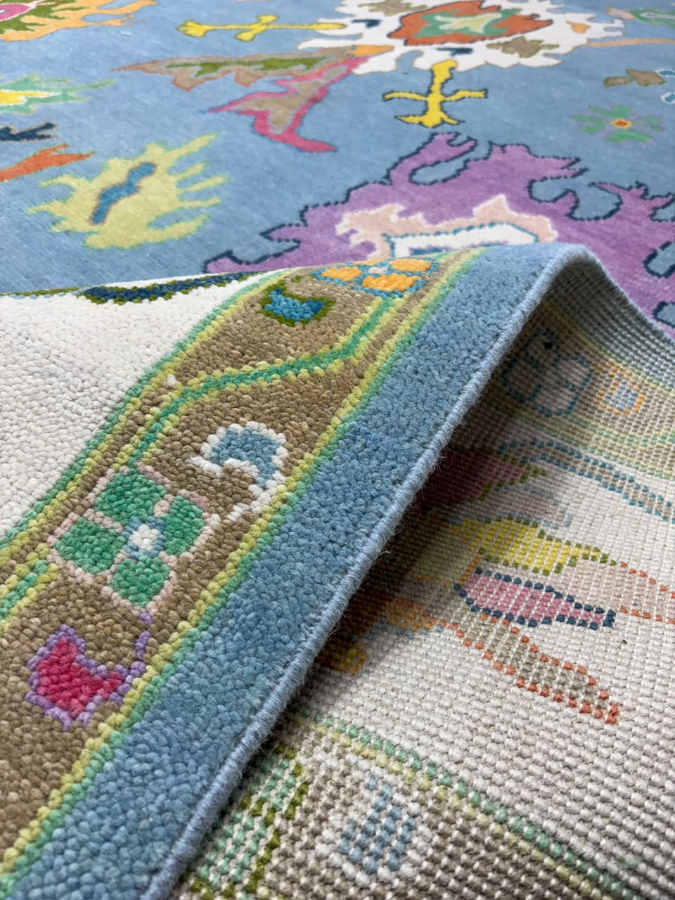 Decorative floral border detail on handmade sky blue wool rug