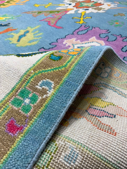 Decorative floral border detail on handmade sky blue wool rug