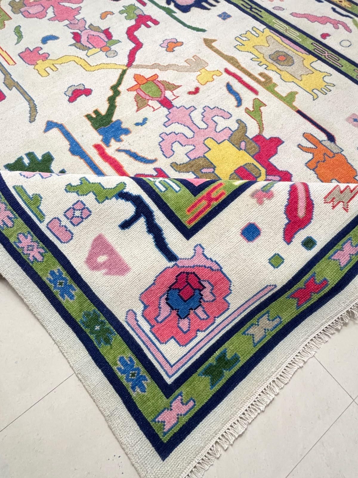 Folded corner of a handmade wool rug showing thick pile, soft texture and handcrafted Scandinavian folk art pattern.