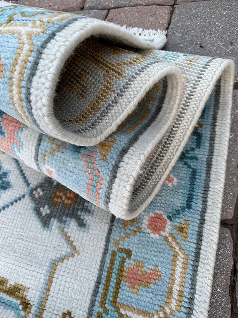 Folded handmade wool Oushak runner showing medium pile thickness and finished edge.
