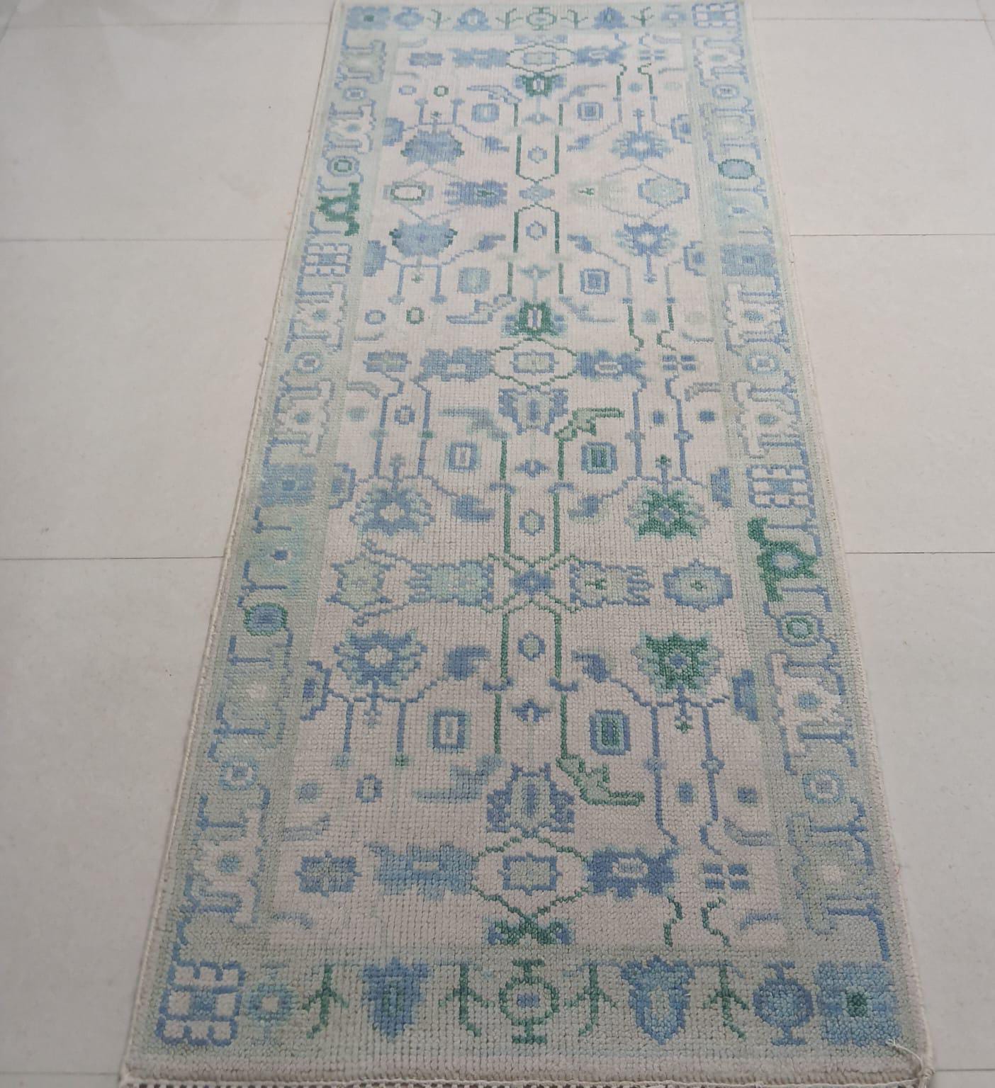 Handwoven blue and green wool runner rug with tribal geometric pattern