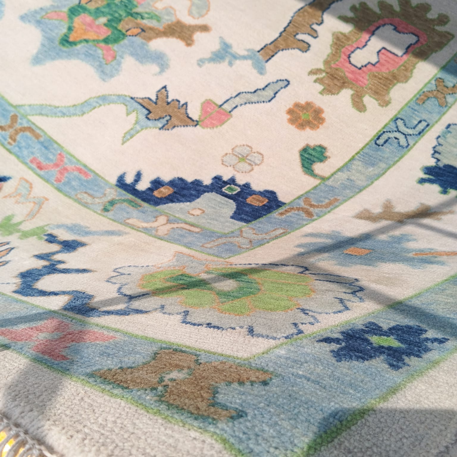 Handwoven Oushak rug in blue and ivory with soft floral motifs and vintage texture