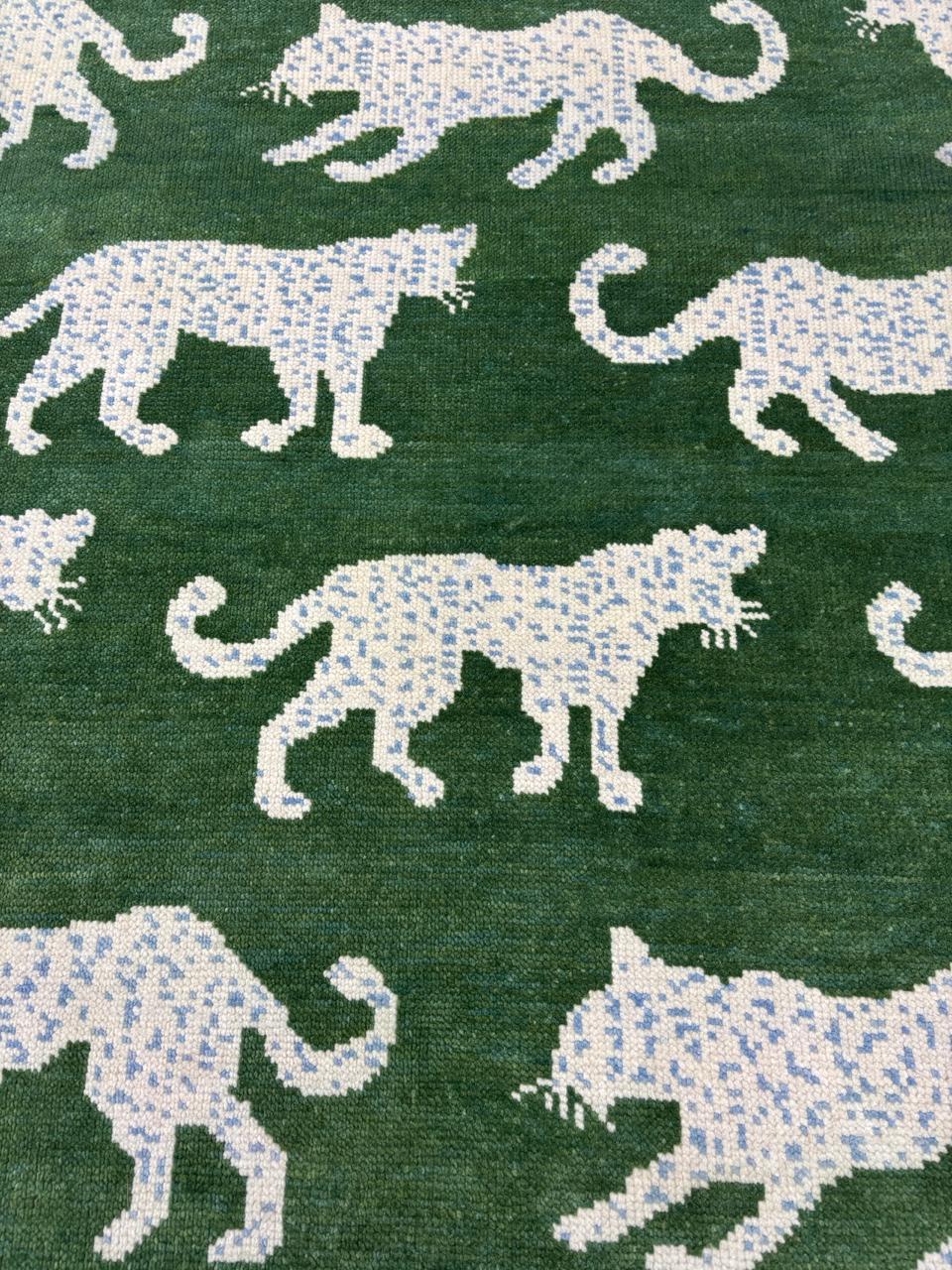 Handwoven green wool rug with repeating leopard motif
