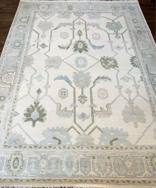 Handwoven ivory and blue Oushak wool area rug with soft traditional floral motifs