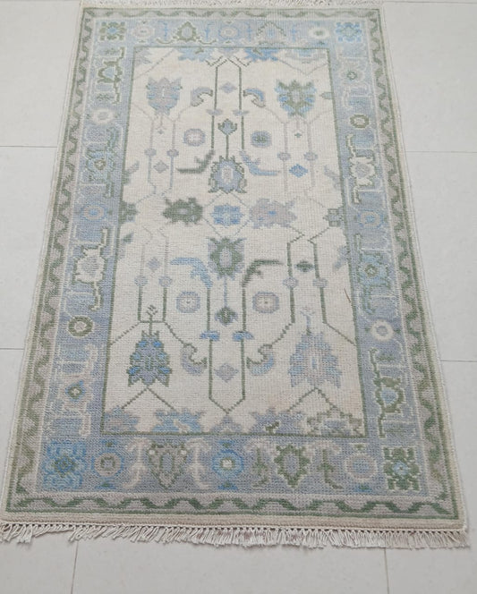 Handwoven ivory and blue Oushak wool area rug with traditional Turkish floral design