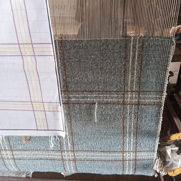 Artisan weaving process behind a hand-knotted Oushak rug, showcasing traditional craftsmanship at the loom