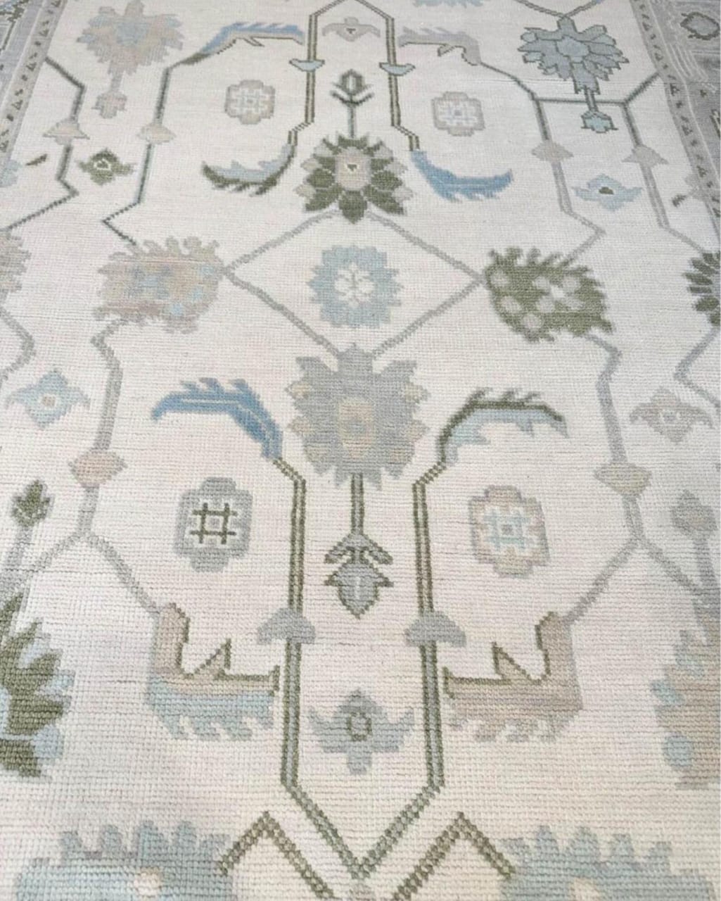 Traditional floral center detail of handwoven Oushak wool rug in soft ivory and blue tones