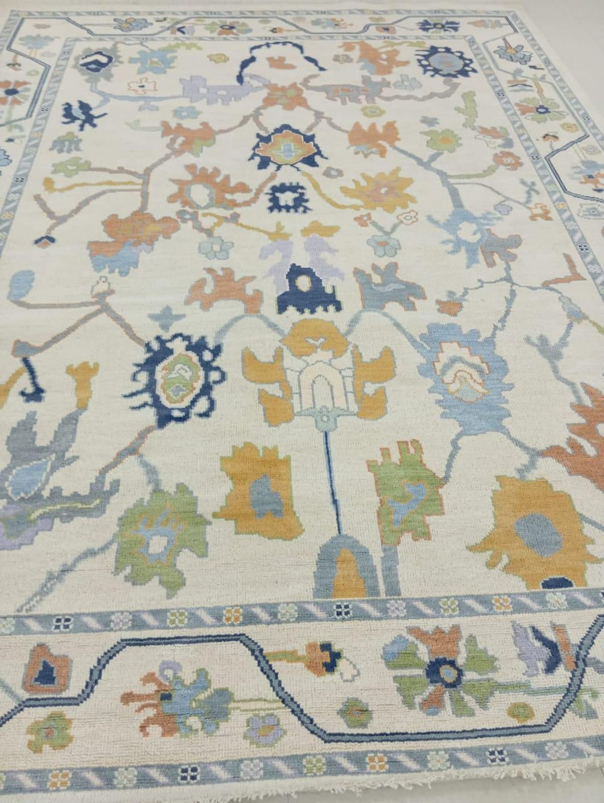 Handwoven white and Blue Oushak wool area rug with antique floral design on ivory background