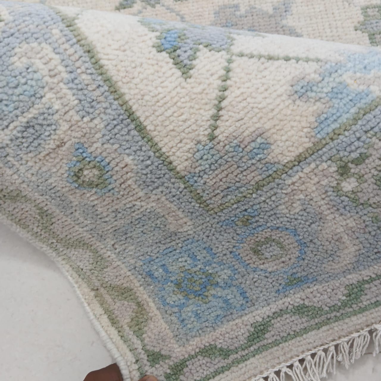 Close-up of a textured rug with geometric pattern and fringes.