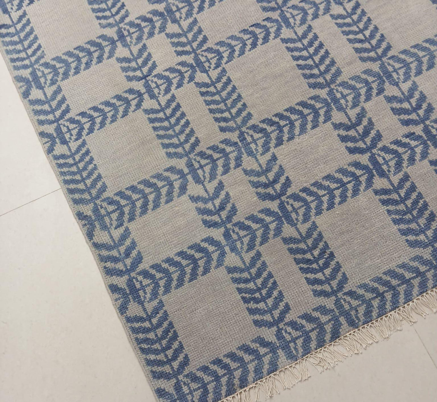 Blue and ivory handwoven wool area rug with fringe detail and geometric pattern