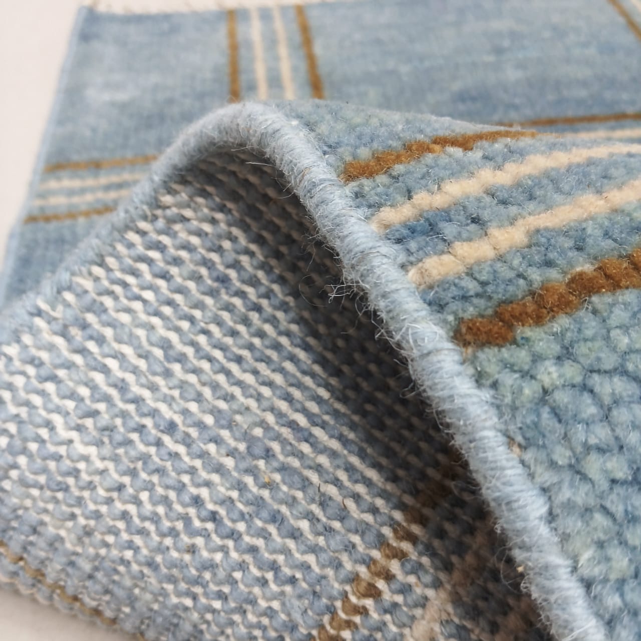 Folded corner of blue handwoven wool rug showing thickness and quality