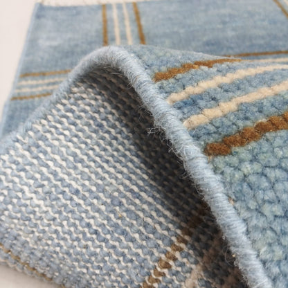 Folded corner of blue handwoven wool rug showing thickness and quality