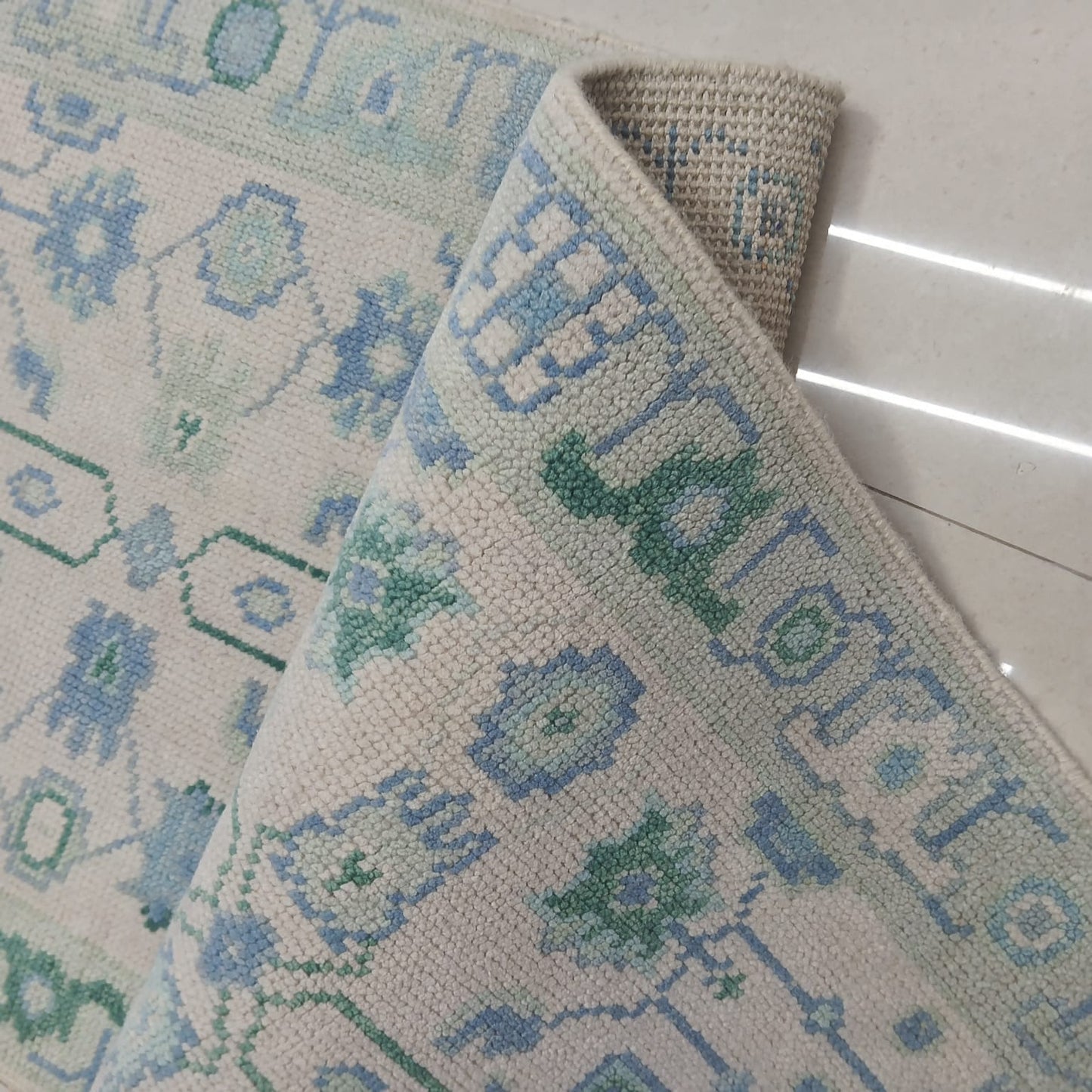 Rolled edge detail of handwoven wool runner rug showing thickness and craftsmanship