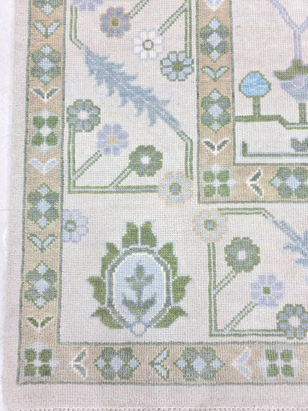 Ivory blue floral rug showing traditional botanical motifs and detailed decorative border