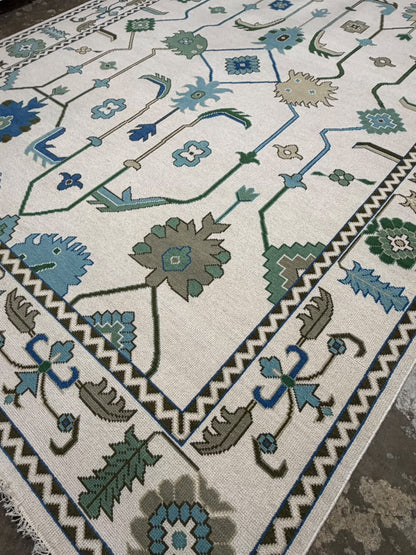 Decorative blue and green border with ivory fringe on a traditional floral rug.