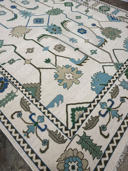 Angled view of an ivory traditional rug with blue and green botanical patterns.