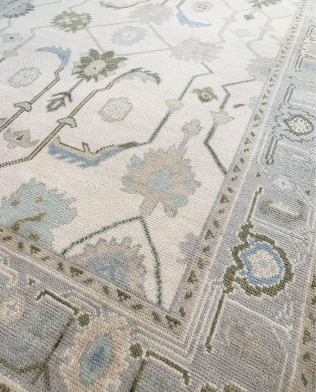 Close-up of handwoven Oushak wool rug showing ivory and blue border details