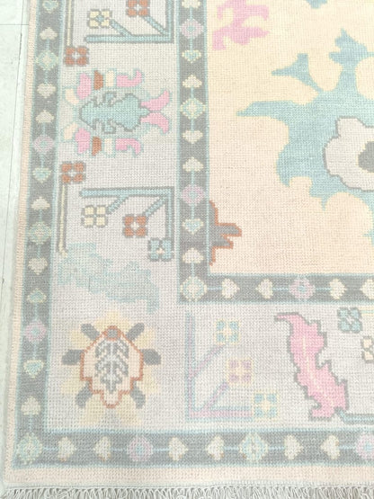 Border detail of ivory and pastel Oushak style area rug