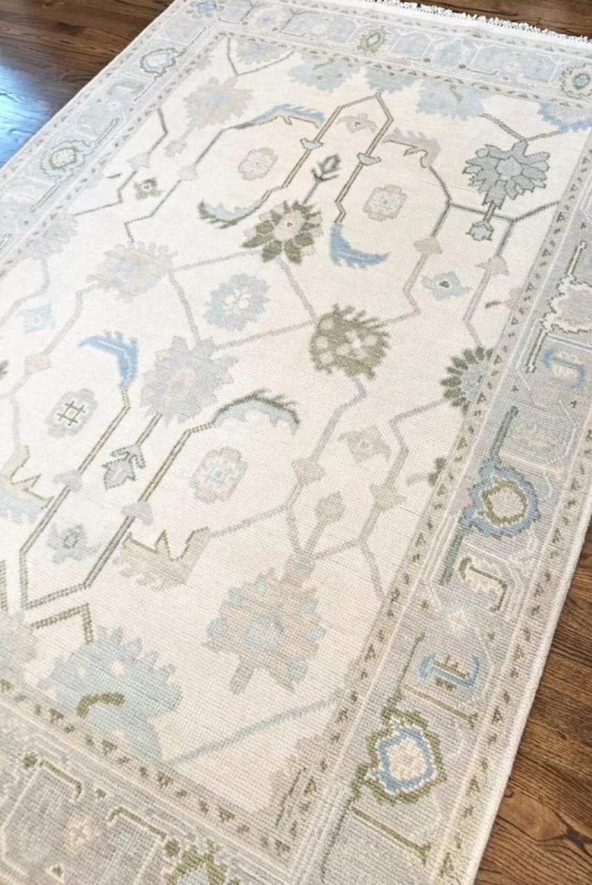 Handwoven ivory Oushak wool area rug styled on a wooden floor in a living space